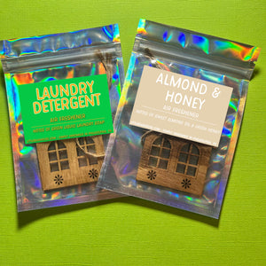 Air freshener in the shape of a house with cathedral style windows in sealed bag