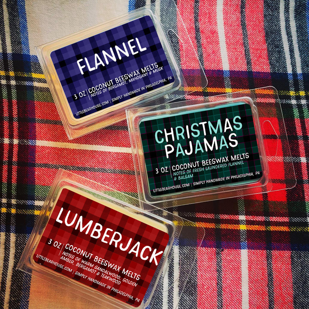 3 oz Flannel, Christmas Pajamas, and Lumberjack beeswax and coconut wax melt on flannel background with a white base and black, blue, red, green, and yellow flannel pattern. Simply handmade in Philadelphia, PA.