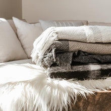 Load image into Gallery viewer, Cashmere Blankets folded on a luxury linen and fur bed with a cedar bed tray wax scent
