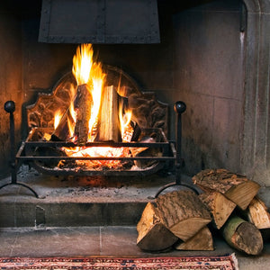 Crackling fire in a stone fireplace with chopped wood beside it wax scent